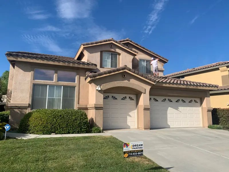 Professional exterior painting transformation showing two-story stucco home in Riverside CA with fresh paint on walls, trim, and garage doors by Dream Painting contractors