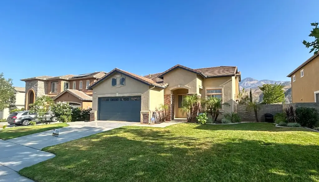 Front view of Highland CA home before exterior painting showing faded yellow stucco and blue garage door needing professional painting services