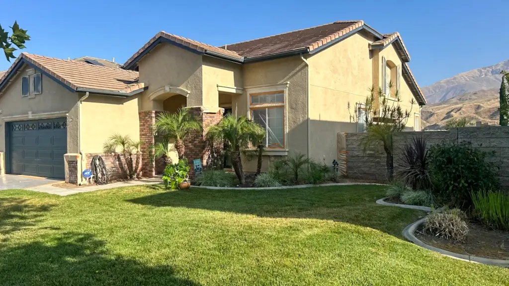 Highland CA Spanish-style home exterior before renovation showing original yellow paint and mountain views