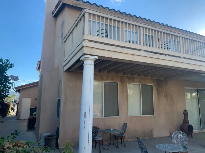 Patio area exterior painting transformation featuring painted support columns, stucco walls, balcony underside, and coordinated color scheme by Dream Painting