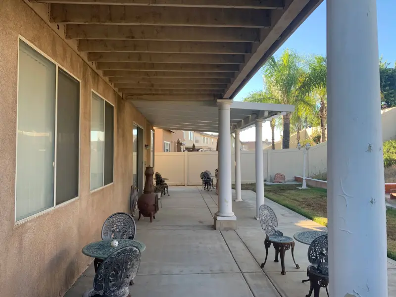 Extended patio coverage showing professional painting of support beams, ceiling surfaces, columns, and integration with landscaping in Riverside home