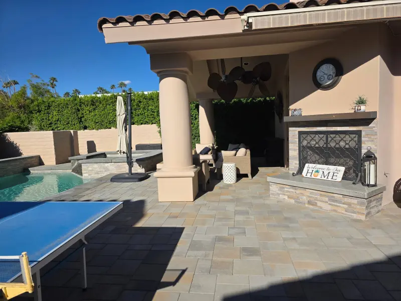 Freshly painted backyard patio with columns, pool, and outdoor fireplace at a residential property in Indian Wells, CA 92210.