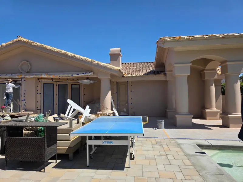 Exterior painting preparation in progress at a luxury home in Indian Wells, CA 92210, with painters masking windows and surfaces before applying fresh paint.