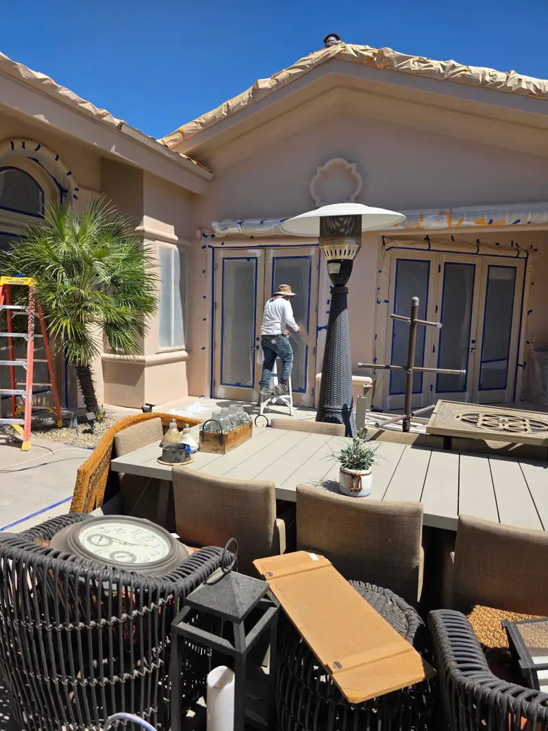 Painter preparing and masking windows and trim during exterior painting setup at a residential property in Indian Wells, CA 92210.
