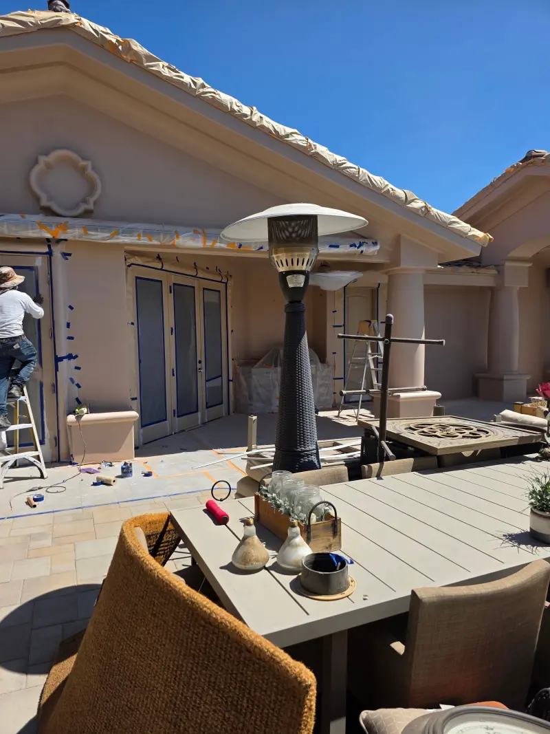 Painter masking windows and architectural details during exterior painting preparation at a residential property in Indian Wells, CA 92210.