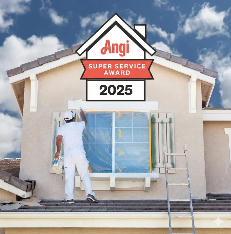 Professional exterior painter from Dream Painting applying fresh white paint to a second-story window frame of a beige home, with a large 2025 Angi Super Service Award badge displayed above the house, under a bright blue sky with clouds.